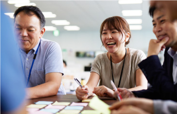 女性社員が男性社員と笑いながら会話している様子